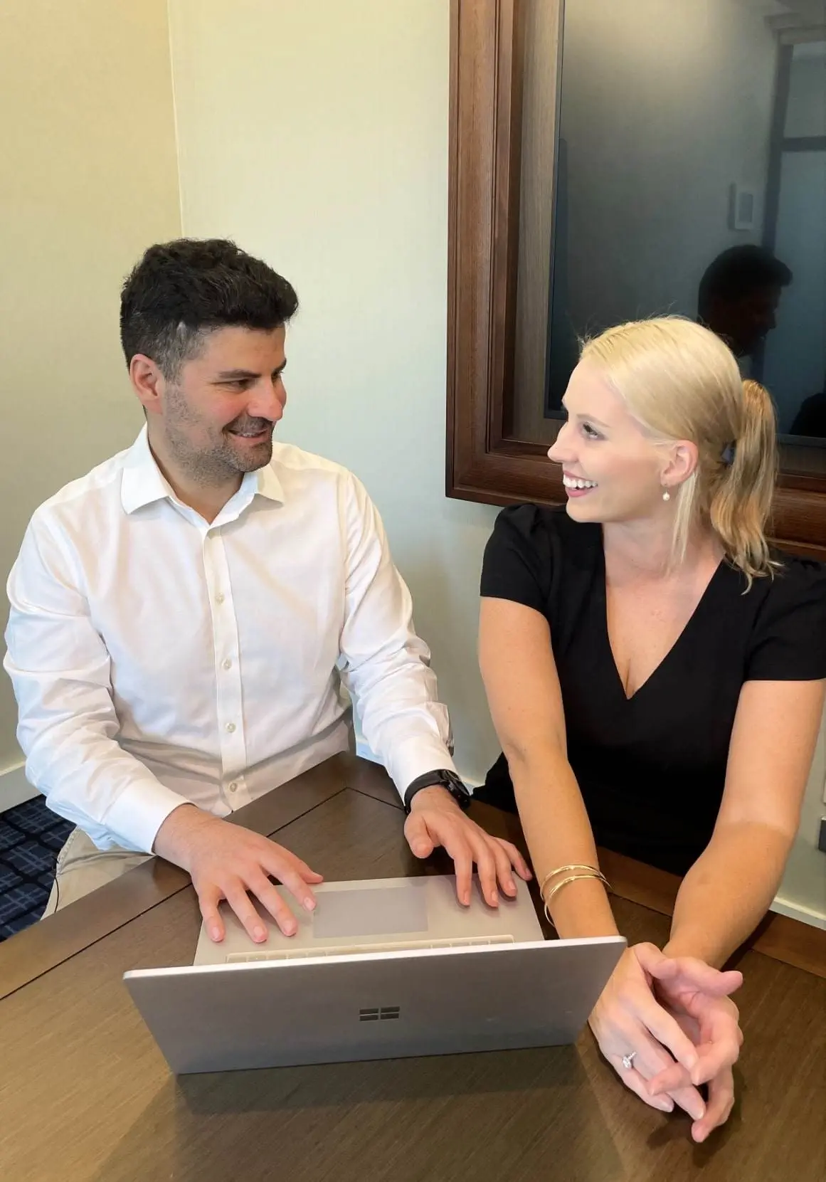 Two business colleagues collaborate on a laptop, discussing a project.