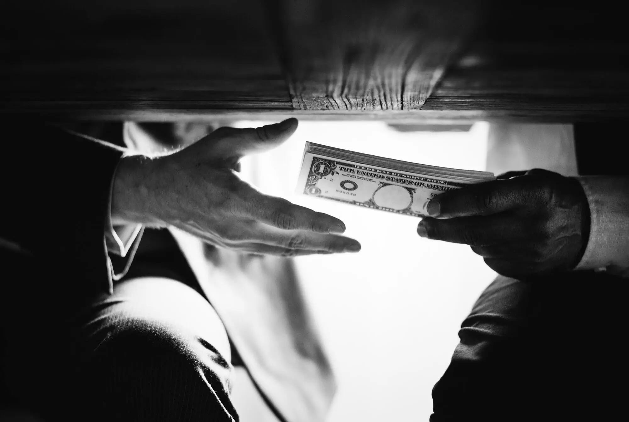 Undercover hand-off of cash, illustrating risks of money laundering and terrorism financing.