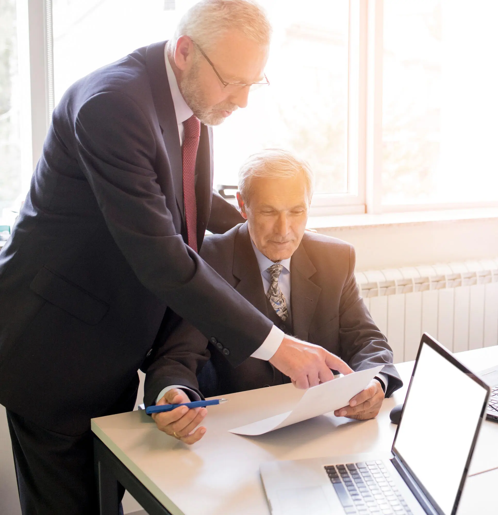 Two businessmen review documents, discussing AML compliance in Australia.