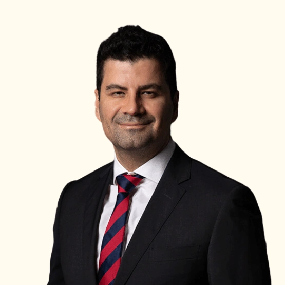 Headshot of a man in a dark suit and red and navy striped tie.