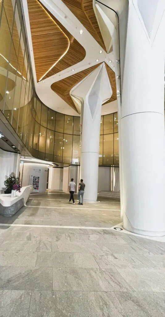 Modern AML House lobby with soaring columns and wood-paneled ceiling.
