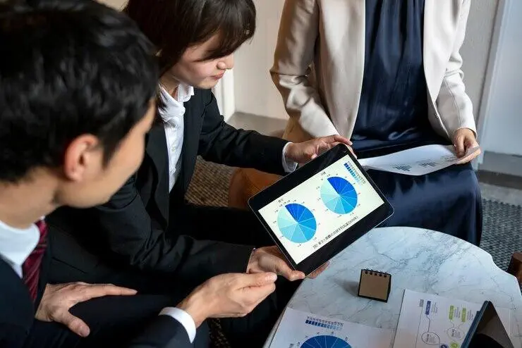 Business people reviewing financial data on a tablet, discussing AML/CTF compliance.