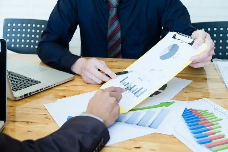 Businesspeople reviewing financial charts and graphs, discussing AML/CTF compliance.