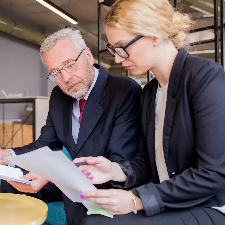 Business colleagues review documents, discussing AML/CTF compliance.