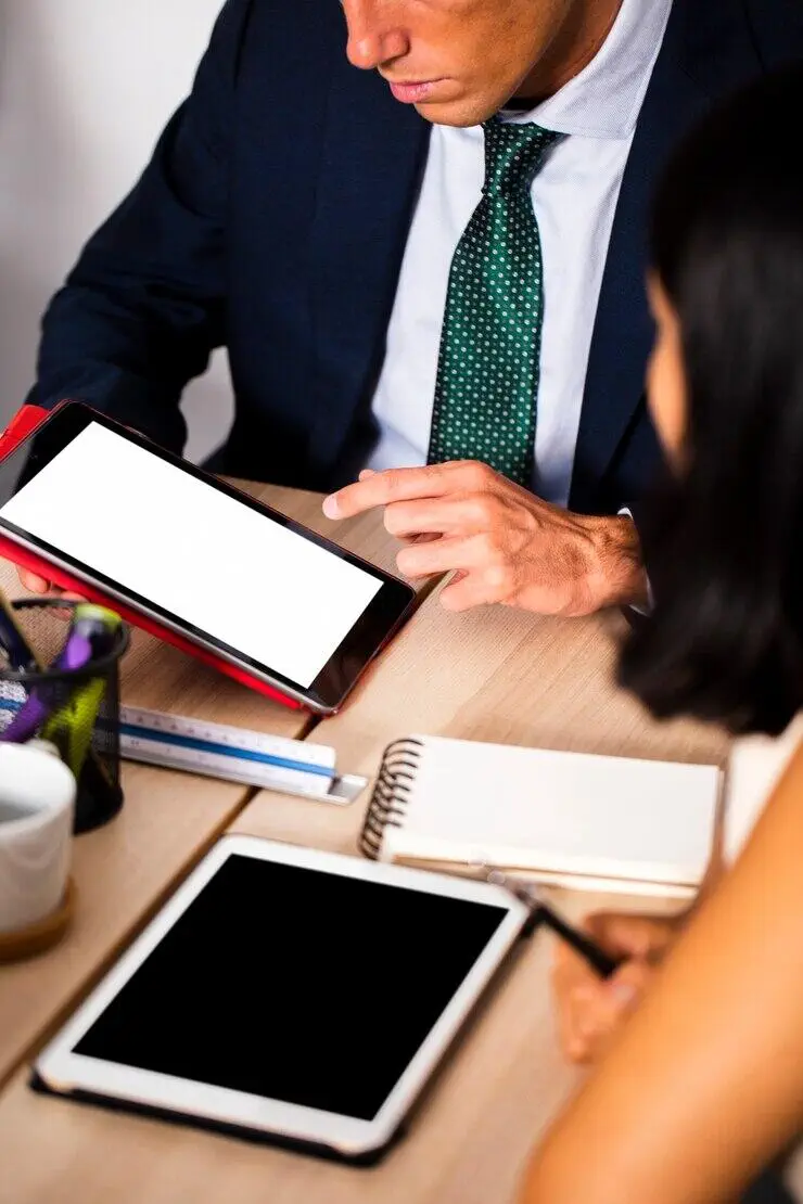 Businesspeople reviewing tablet; AUSTRAC AML/CTF compliance discussion.