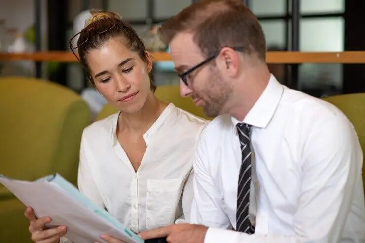 Two business colleagues review documents, discussing AML/CTF compliance.
