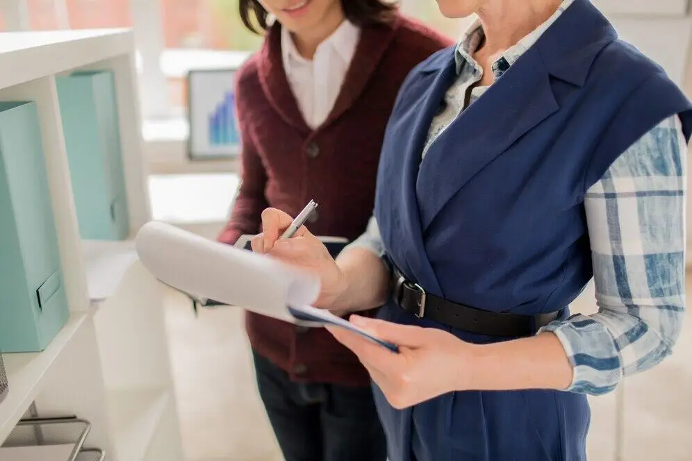Two businesswomen reviewing documents, discussing Australian AML/CTF compliance.