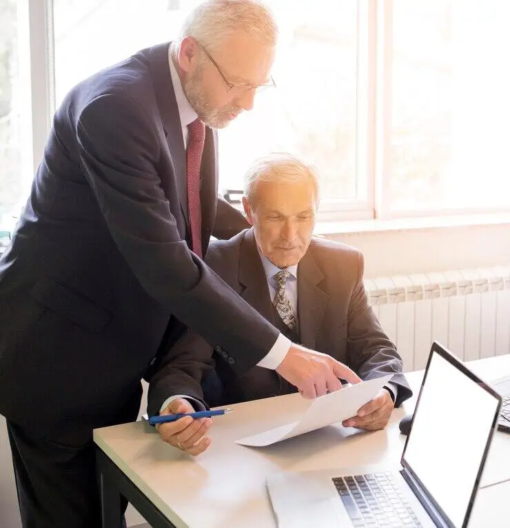 Two real estate agents review documents, discussing new AML/CTF compliance.