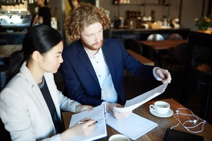 Two businesspeople review documents, discussing AML/CTF compliance in Australia.