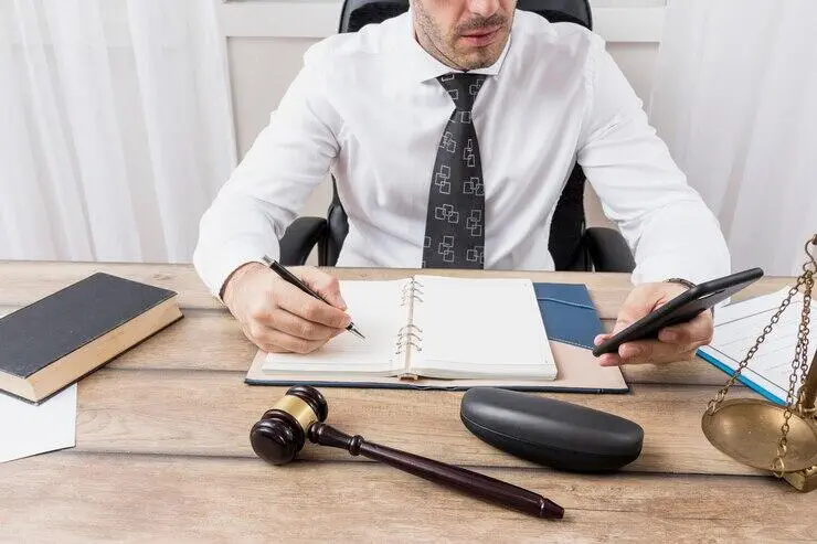 Lawyer reviewing documents and using phone at desk, ensuring Australian AML compliance.