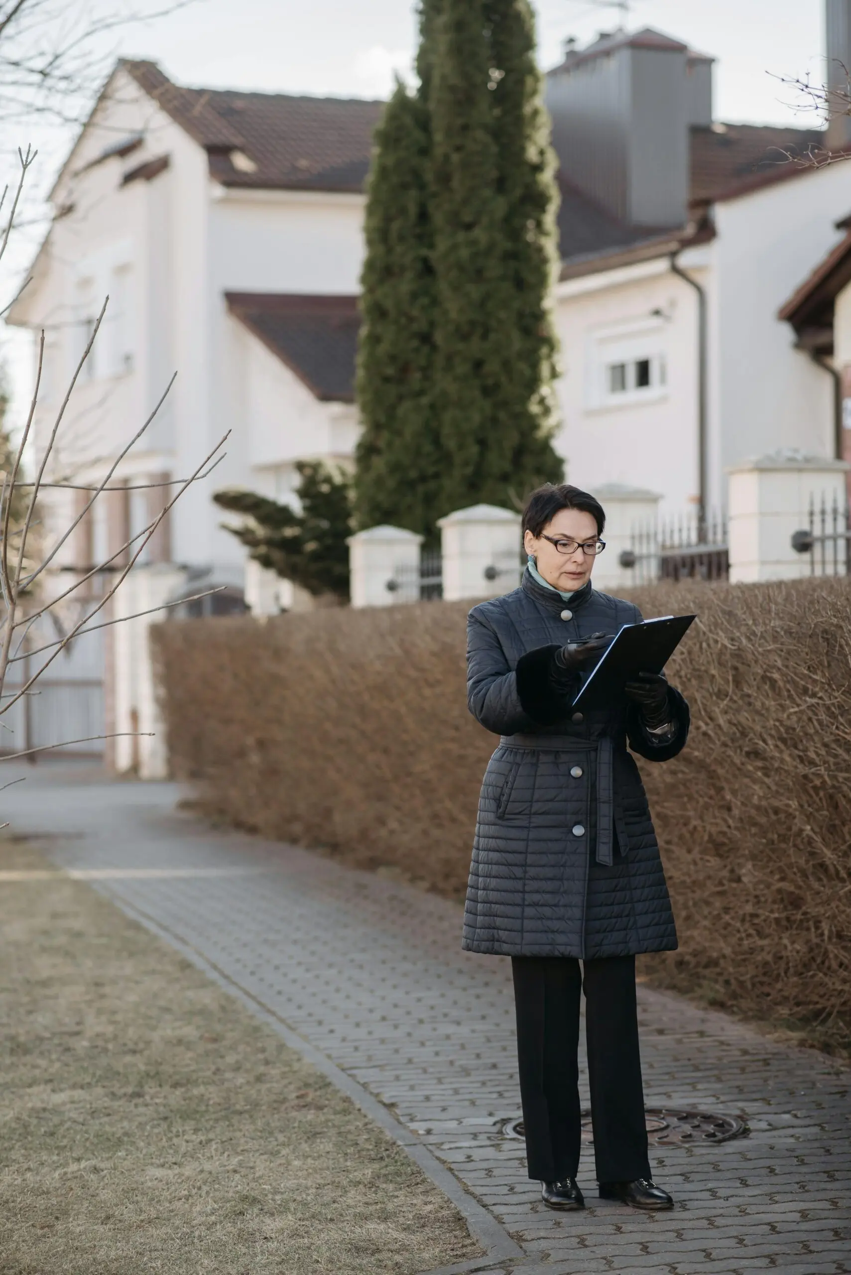 Woman reviewing documents outdoors near a house.